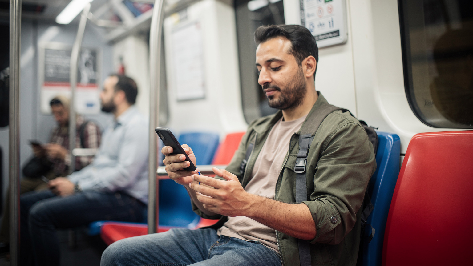 Un viajero, de unos 30 años, en el metro de El Cairo, con la aplicación Careem o Uber abierta en su teléfono, mostrando cómo la eSIM facilita la navegación en el transporte público. Los asientos y otros pasajeros están ligeramente desenfocados en el fondo.