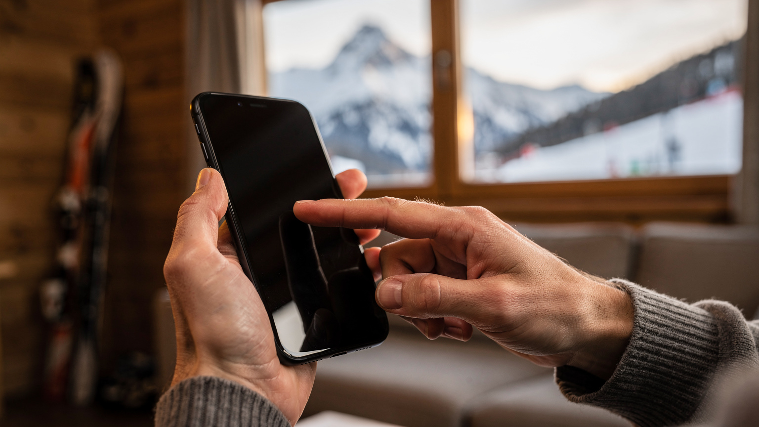 Nahaufnahme von Händen, die ein Smartphone halten und eine eSIM-Installations-App bedienen, mit einer unscharfen Schweizer Berglandschaft im Hintergrund.