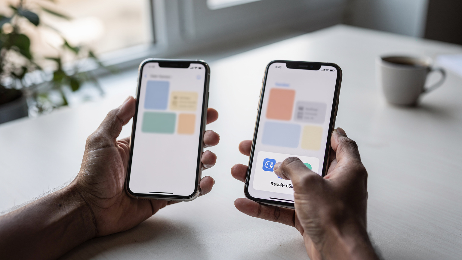 Nahaufnahme von Händen, die zwei iPhones halten, wobei der Bildschirm des neuen iPhones die eSIM-Übertragungsoption zeigt, während der Finger auf die Bestätigung tippt.