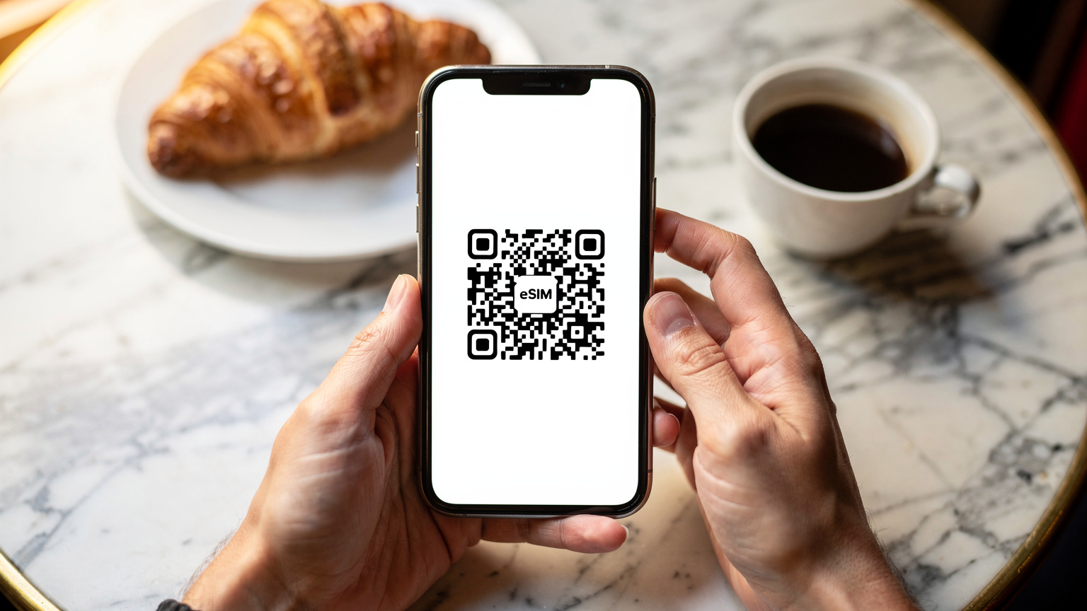 Un gros plan sur des mains tenant un smartphone, avec un QR code eSIM affiché à l'écran, dans un café parisien typique.