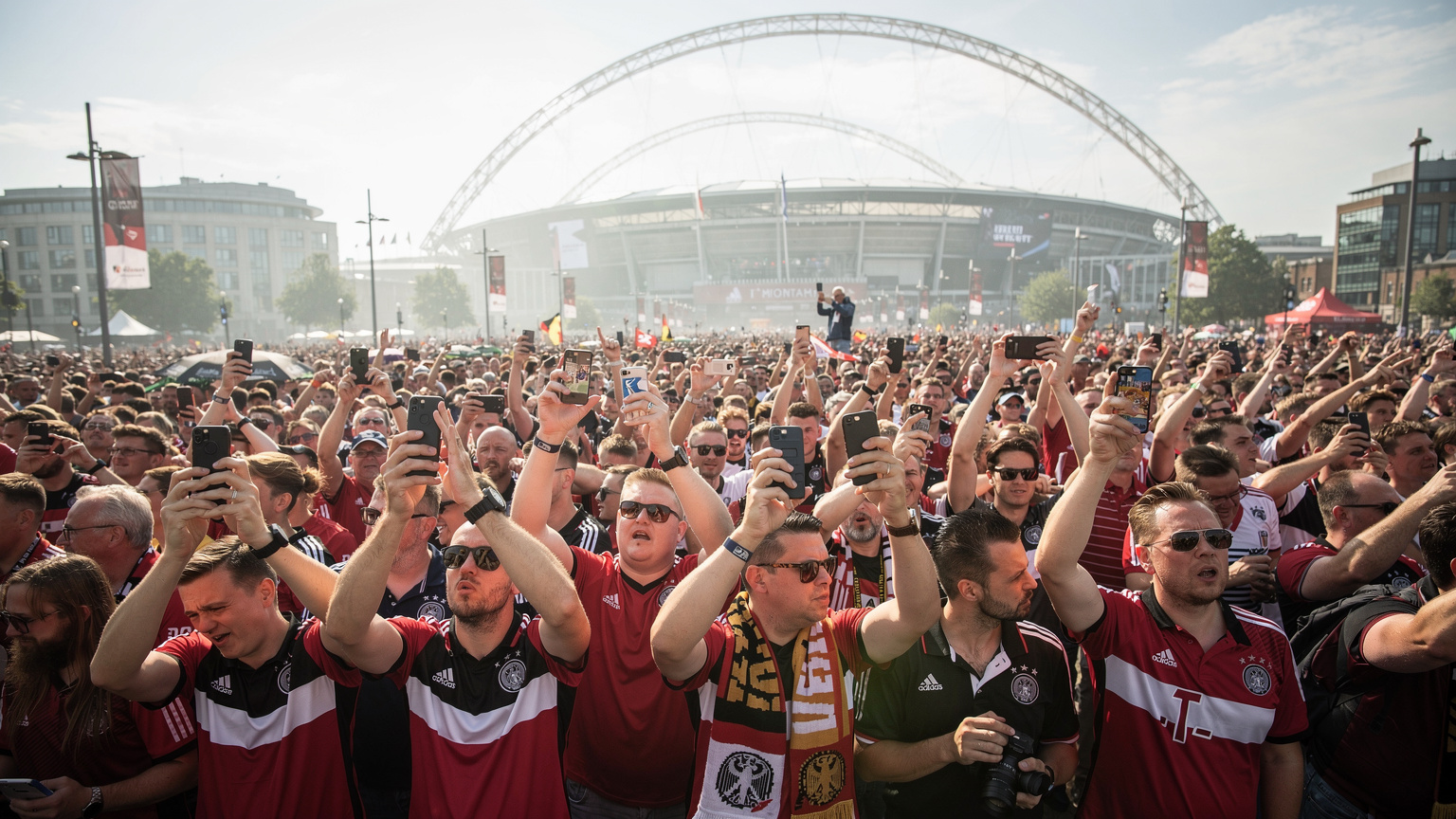 Eine Menschenmenge von Fußballfans in Wembley Park, alle mit Smartphones in der Hand, einige versuchen vergeblich, eine Verbindung herzustellen. Im Hintergrund ist das Wembley-Stadion zu sehen.