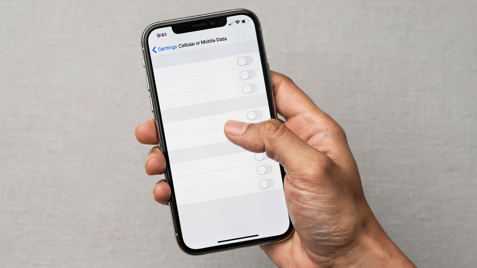 一只手握持最新款iPhone 18(或类似外观的手机),屏幕上显示着iOS 18的蜂窝网络设置界面,eSIM添加和管理选项清晰可见。