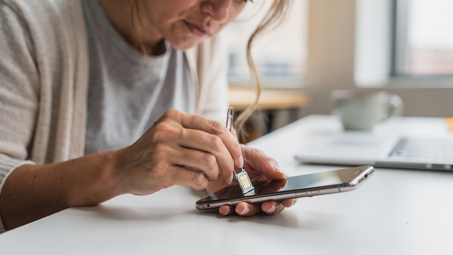 A woman in Austin, Texas, looks frustrated while trying to insert a tiny physical SIM card into her smartphone, highlighting the common difficulty of traditional SIM installation.