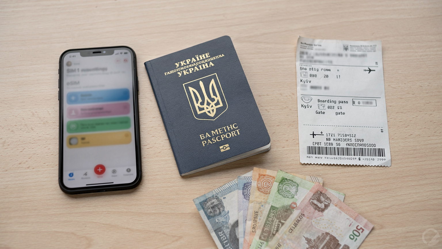 Український паспорт, смартфон з активним профілем eSIM на екрані, авіаквитки та українська гривня на столі, готовий до подорожі.
