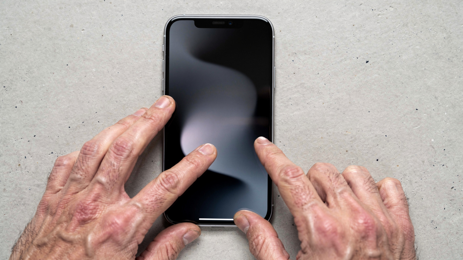 A close-up of a person's hands holding an iPhone 16, navigating through the Settings app with a clear, focused gesture, under soft studio lighting.