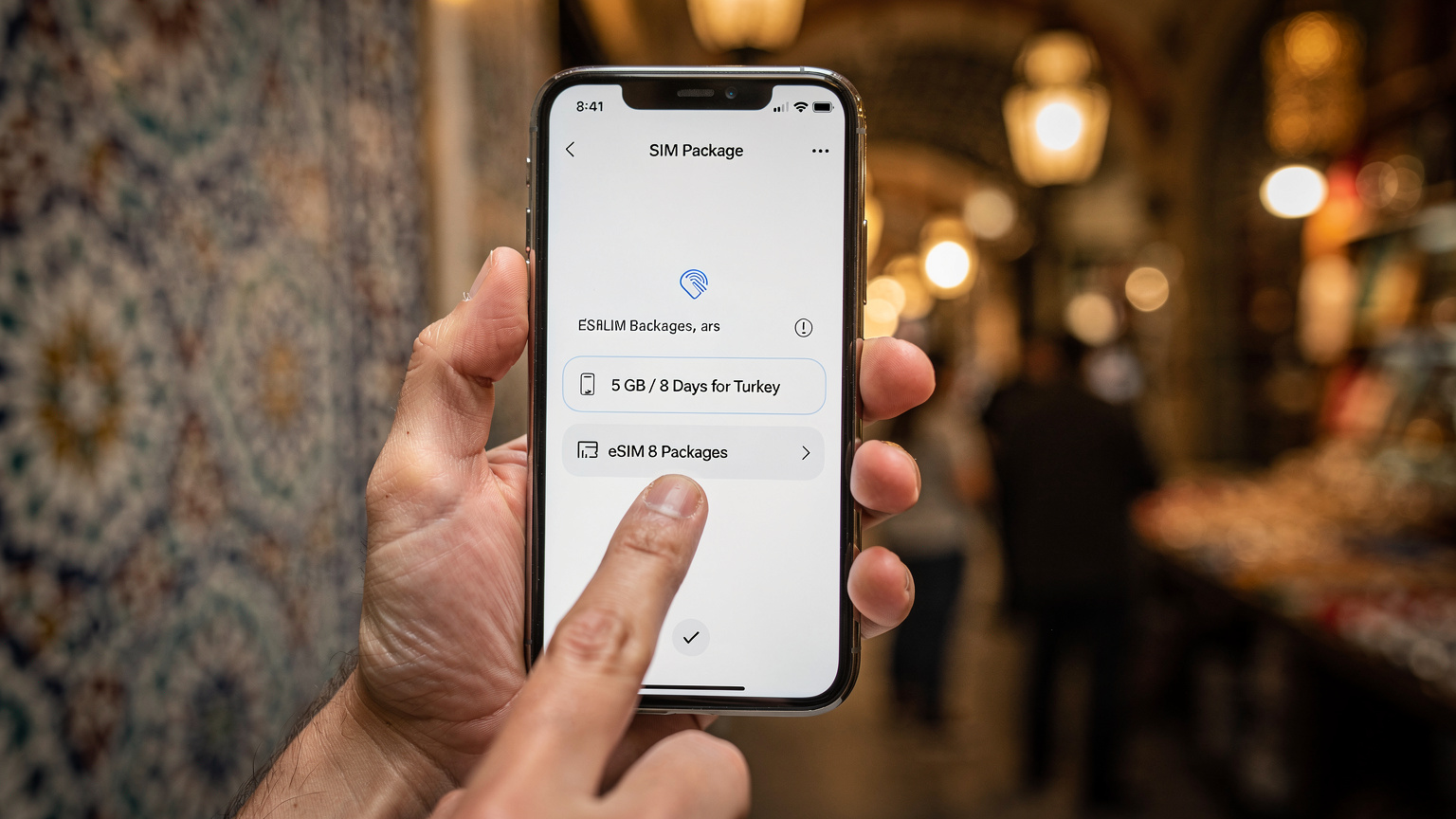 Bir akıllı telefon ekranında Cellesim uygulamasının Türkiye eSIM paketlerini gösteren arayüzü. Telefonu tutan el, parmağını uygun fiyatlı 5 GB/8 Günlük bir paketin üzerinde gezdiriyor, arka planda bulanık bir şekilde Kapalıçarşı'nın hareketli atmosferi hissediliyor.