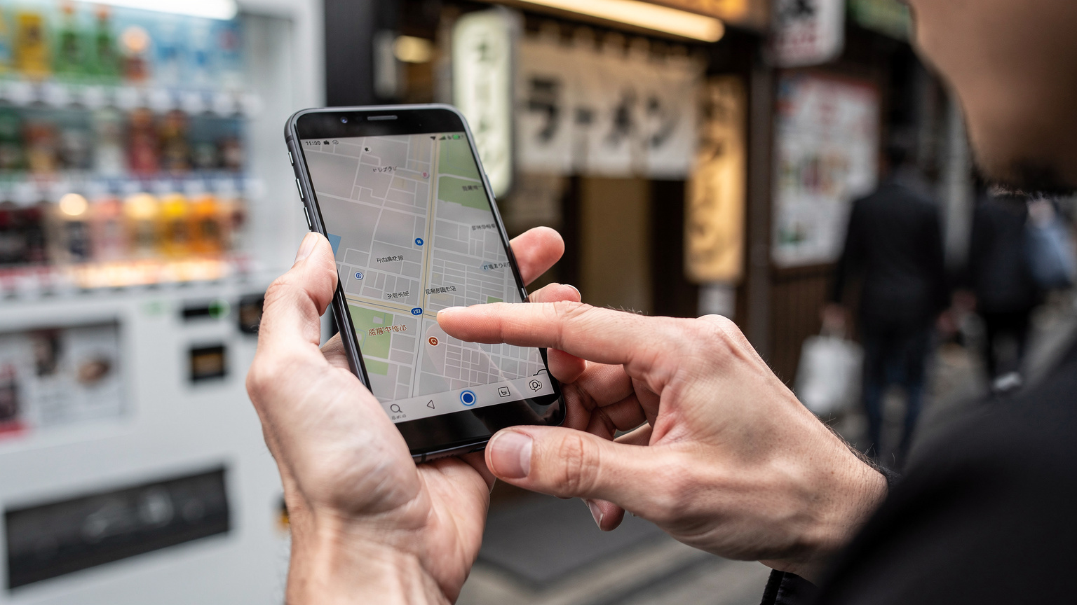 Close-up of hands holding a smartphone, with a blurred map application visible, showcasing the ease of digital navigation in Japan.
