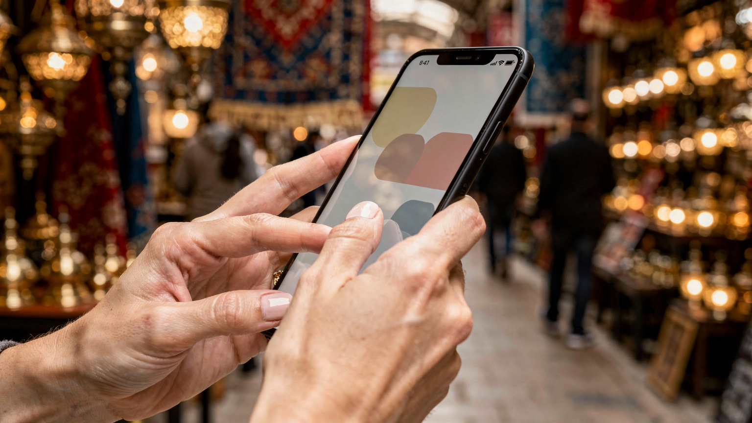 Крупен план на ръце, държащи смартфон с отворен екран за настройка на eSIM, на фона на размазано изображение на Гранд Базар в Истанбул.