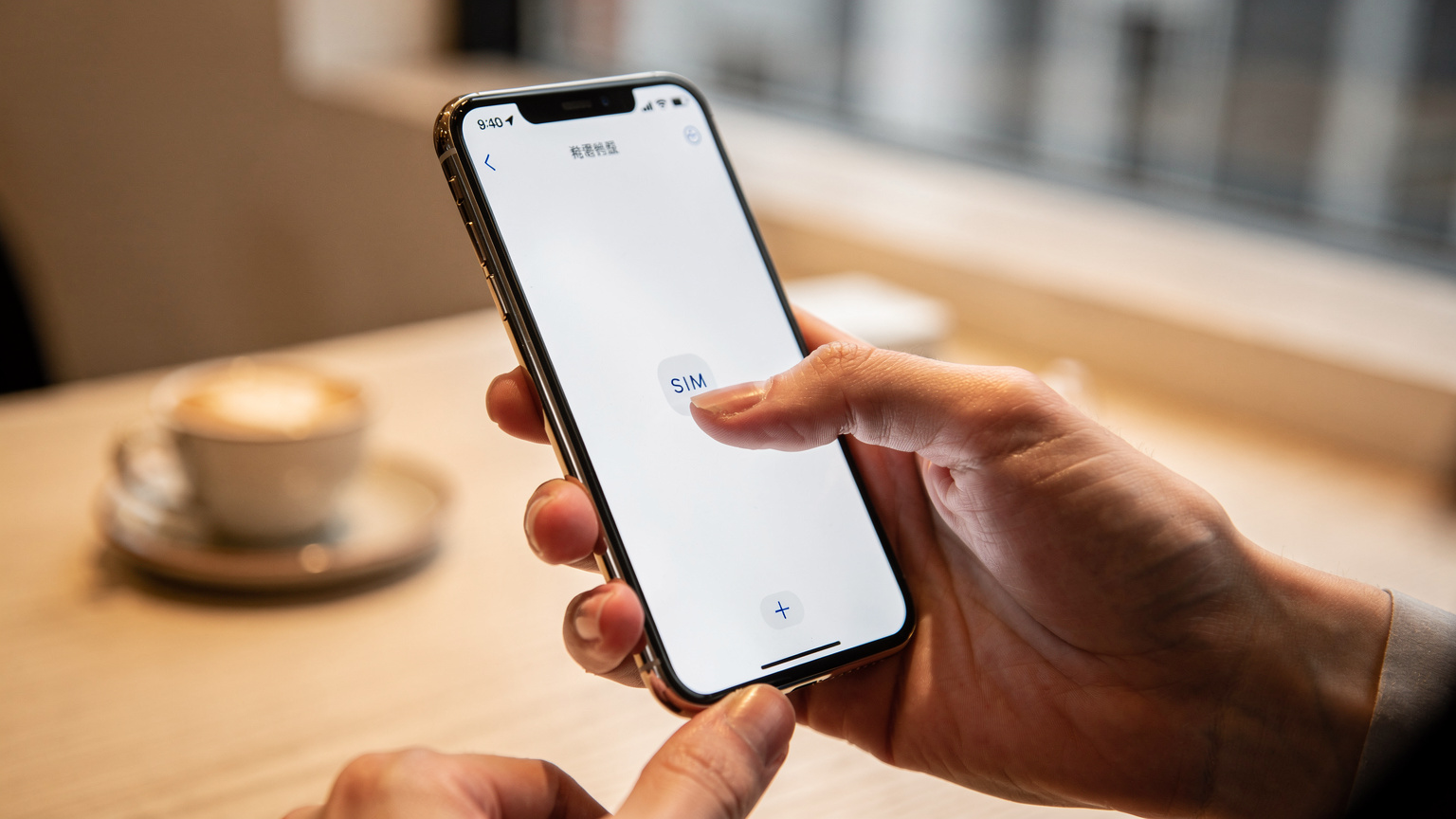 一张iPhone手机屏幕的特写，手指正准备点击eSIM设置界面中的“手动输入详情”选项，背景是模糊的咖啡馆环境。