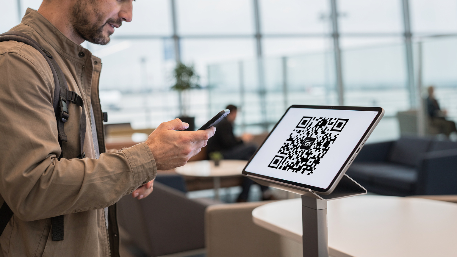 Ένας ταξιδιώτης σκανάρει ένα QR code σε ένα tablet για να ενεργοποιήσει την eSIM του, με ένα smartphone στο χέρι, σε ένα φουτουριστικό περιβάλλον αεροδρομίου.