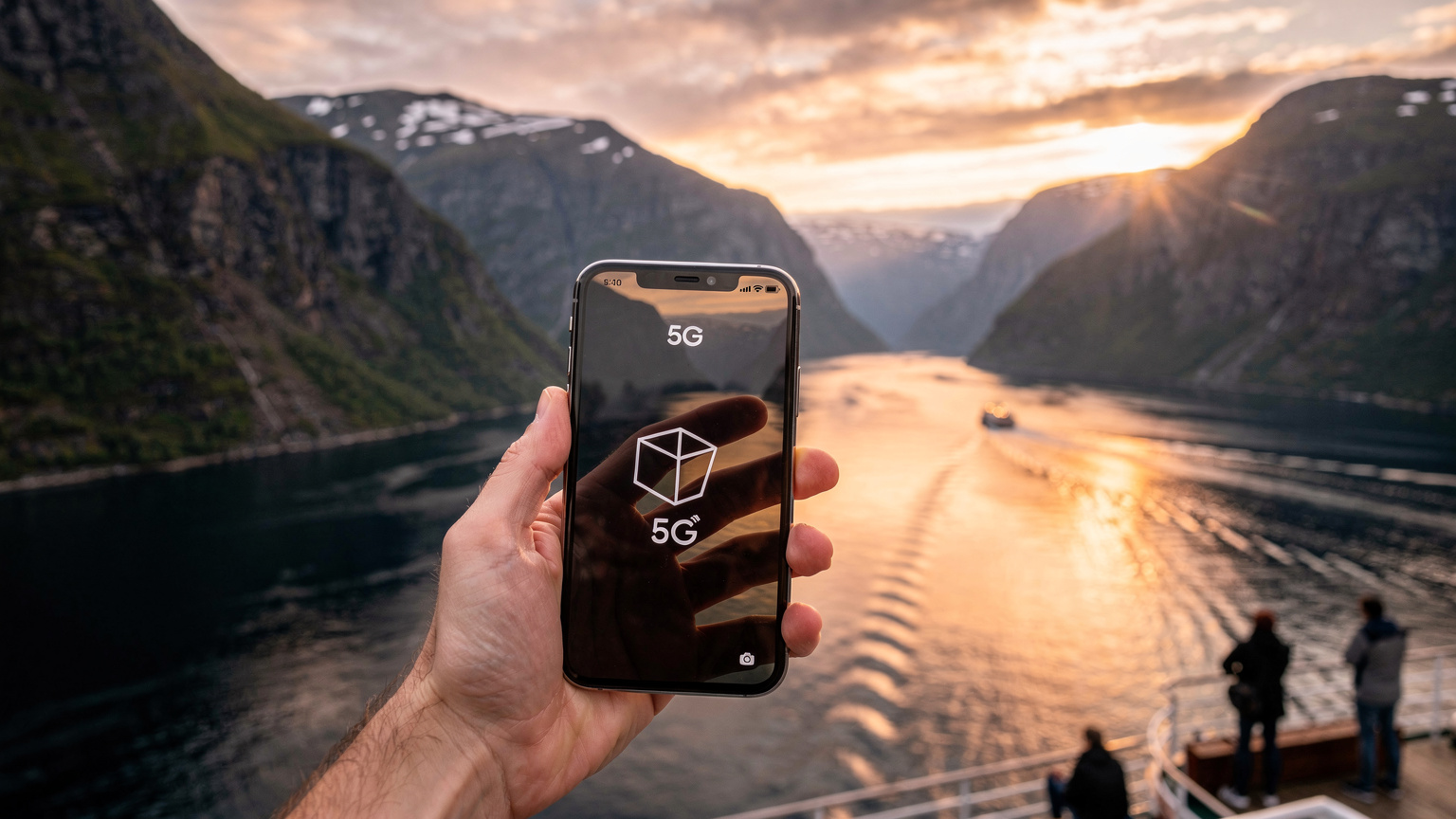 En hånd holder en smartphone op mod en smuk norsk fjord ved solnedgang, telefonen viser fuld 5G-dækning.