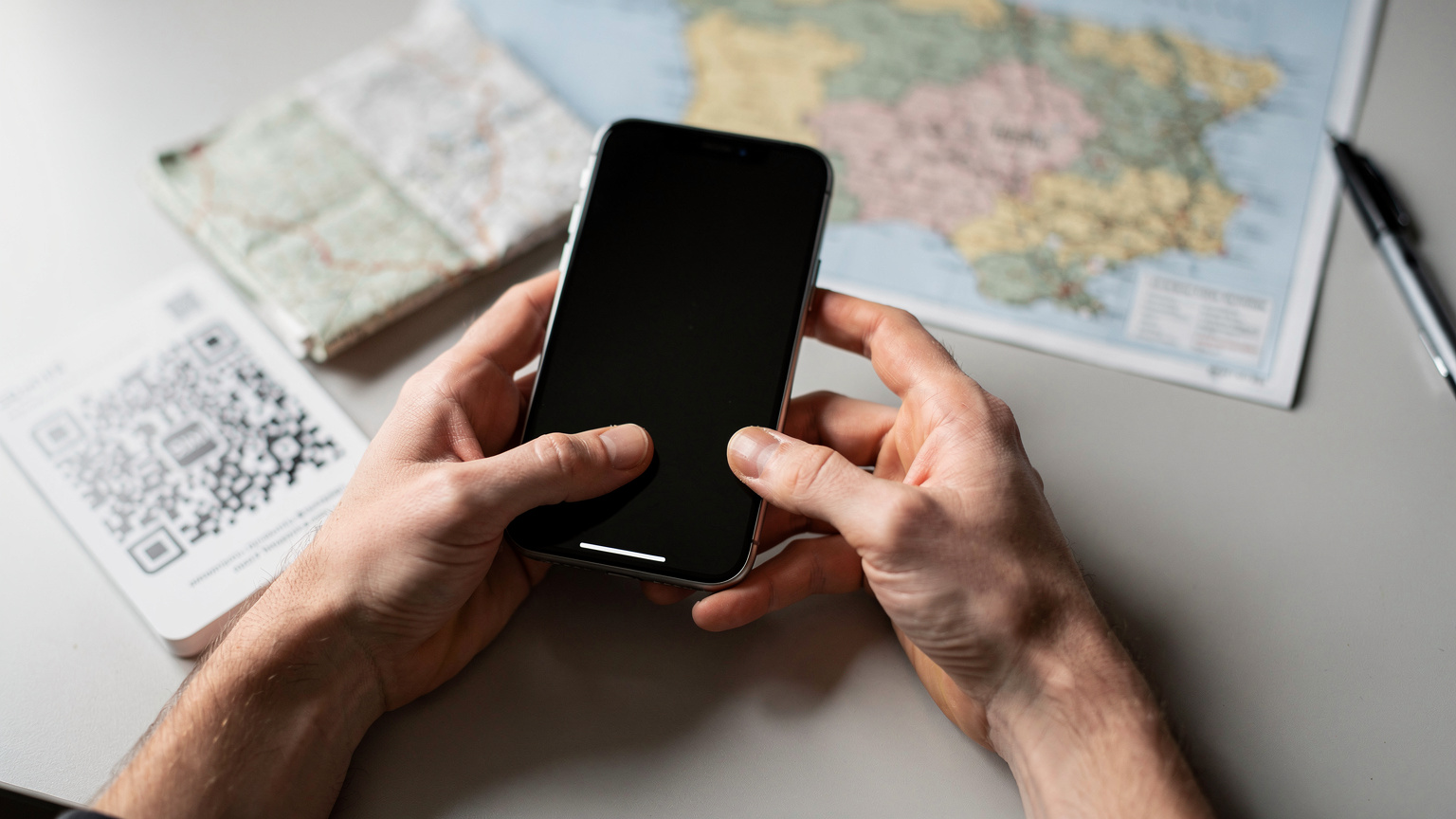 Mãos de um viajante ativando um eSIM num iPhone 18, com um mapa de Portugal desfocado ao fundo, simbolizando a facilidade de conexão antes de explorar.