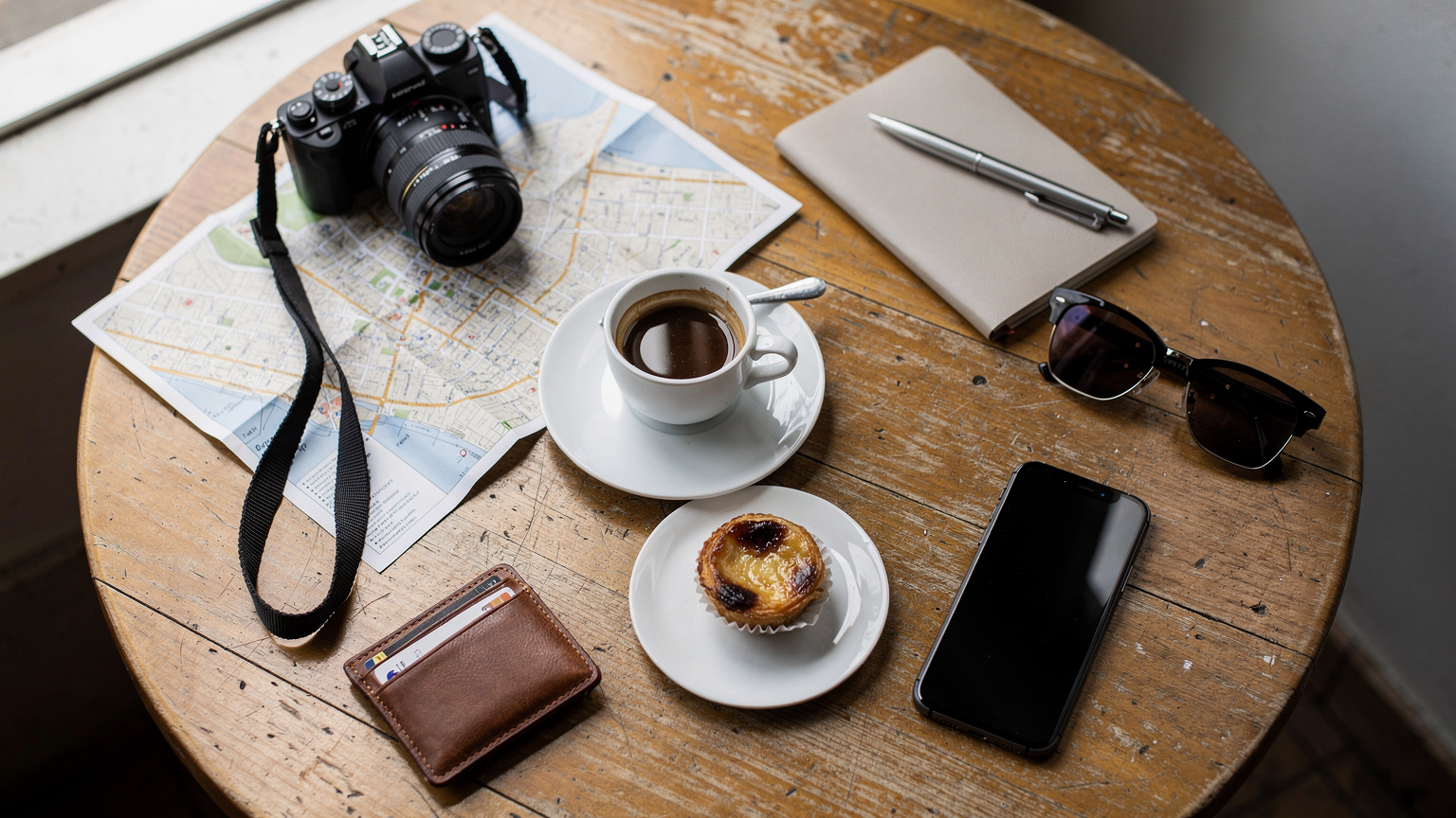 Uma mesa de café em Lisboa com um passaporte, um smartphone com um ecrã de ativação de eSIM e uma bica (café espresso português) ao lado, sugerindo uma viagem sem problemas.