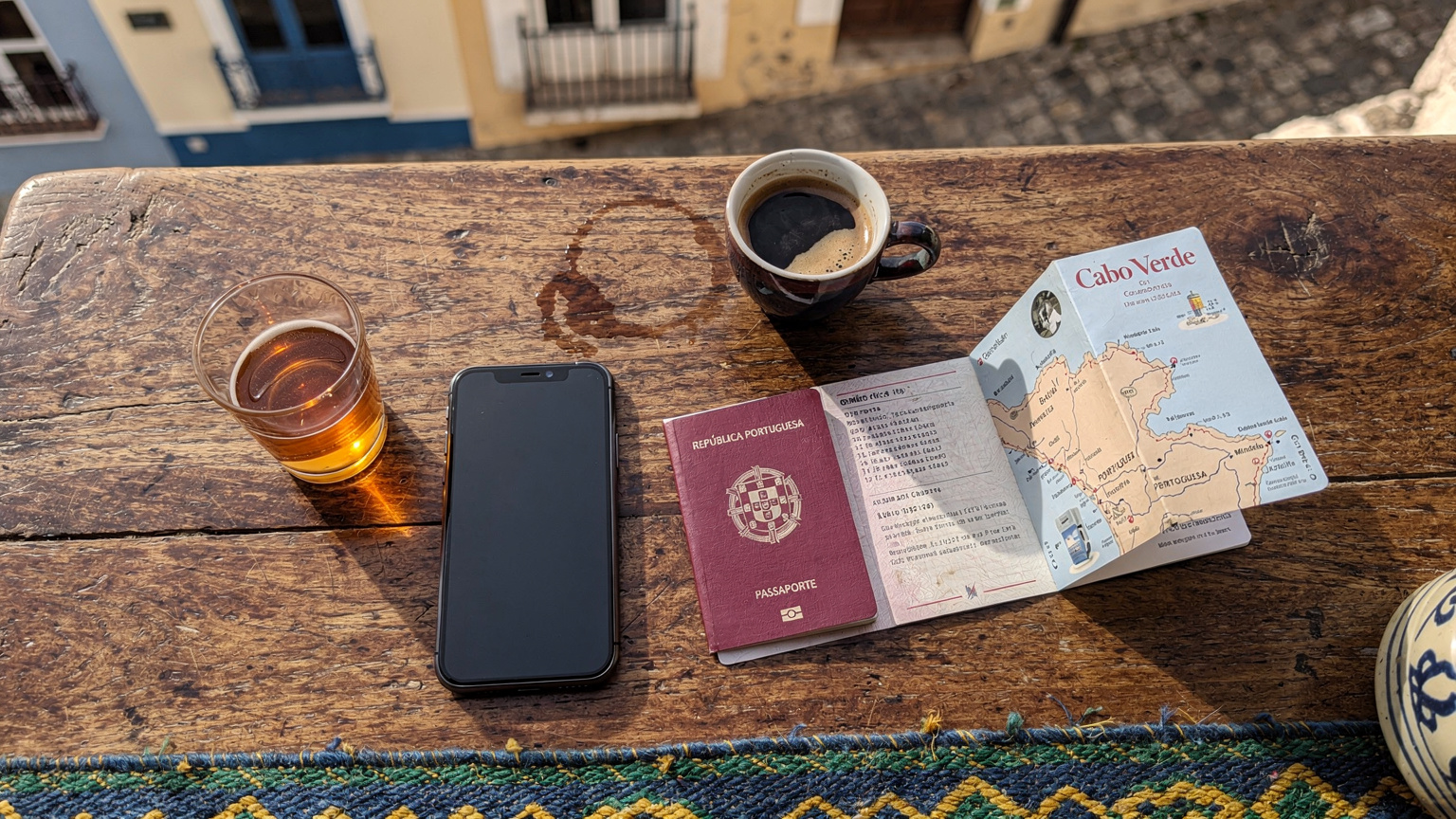 Uma mesa de café em Cabo Verde com um telefone, um passaporte e um mapa aberto, elementos essenciais para um viajante conectado e bem-organizado.