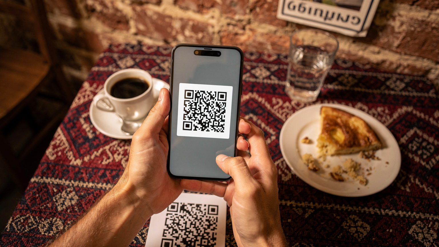 Крупный план рук путешественника, активирующего eSIM на смартфоне Pixel 8 с QR-кодом на экране, сидя в кафе.
