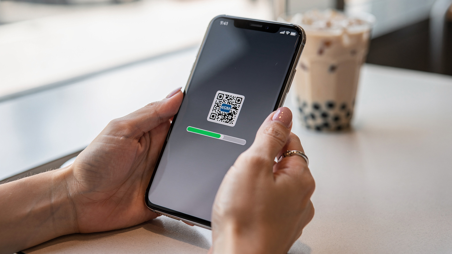 한국인 여행객의 손이 갤럭시 스마트폰으로 eSIM QR 코드를 스캔하는 모습. 화면에는 활성화 진행률 표시줄이 나타나고 있다.