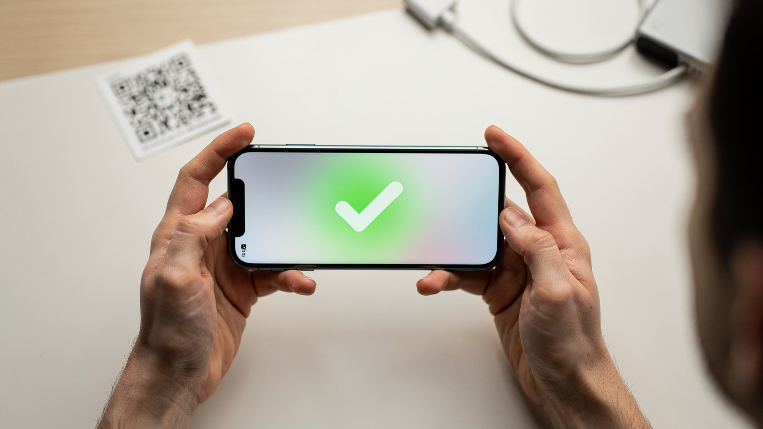Un gros plan sur les mains d'un voyageur tenant un smartphone affichant un écran de confirmation d'activation eSIM, avec un code QR flou en arrière-plan. L'ambiance est lumineuse et moderne.