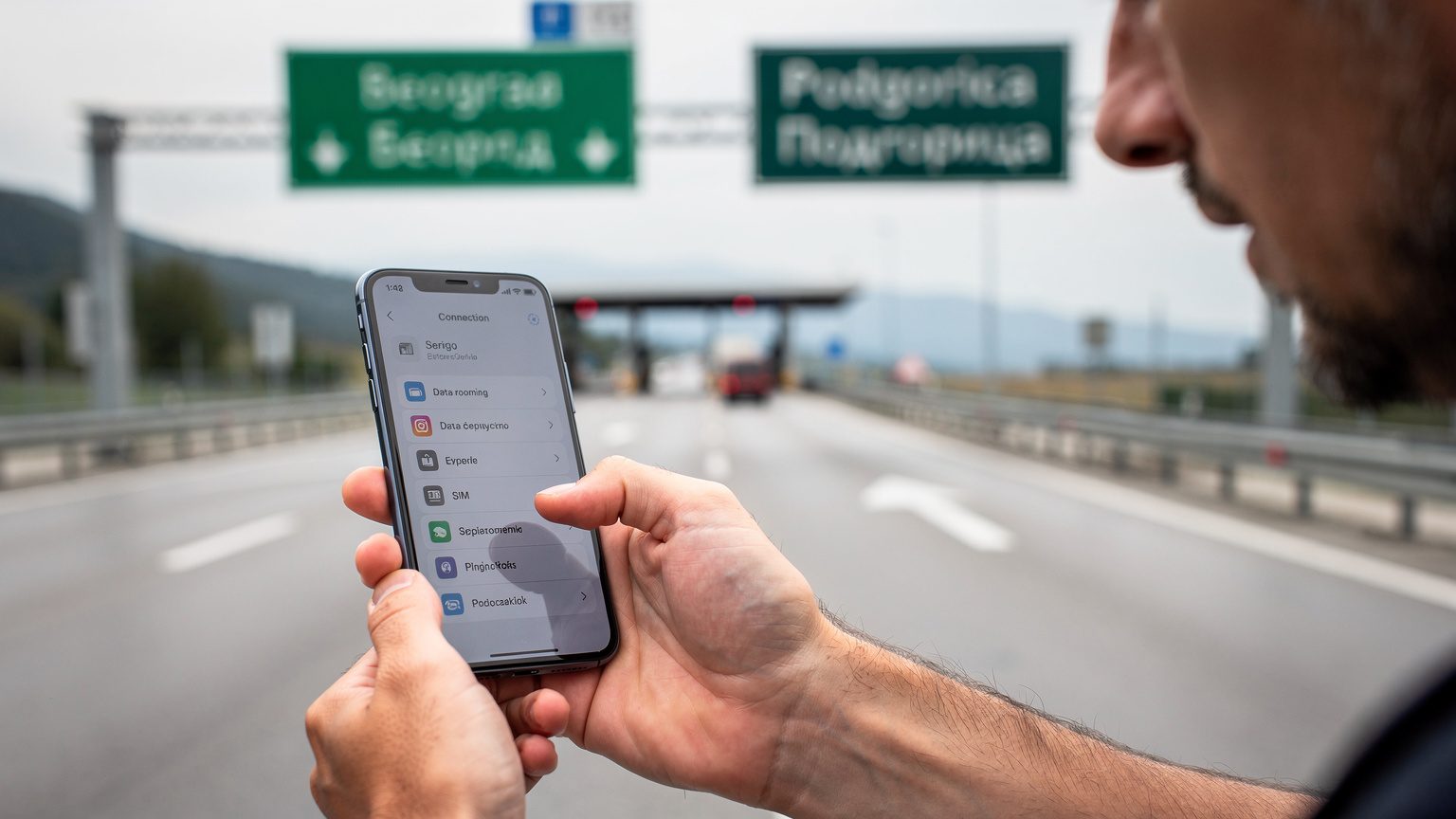O persoană verifică cu atenție setările de conectivitate pe smartphone, înainte de a trece granița dintre Serbia și Muntenegru, cu indicatoare rutiere bilingve în fundal.
