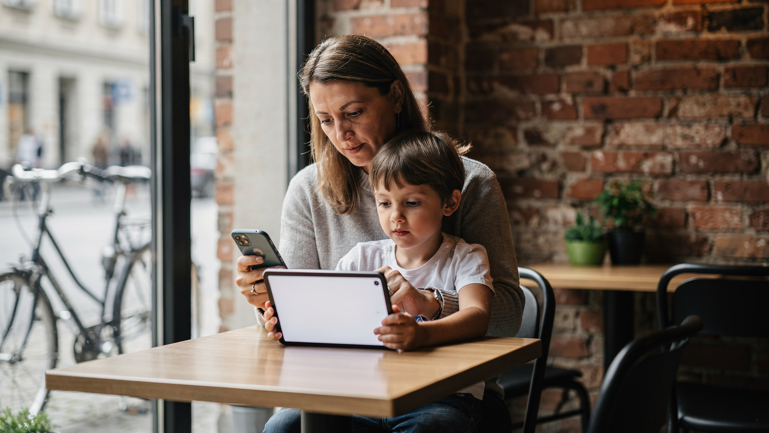 Eine Mutter hilft ihrem Kind im Café in Berlin-Mitte bei der eSIM-Aktivierung auf dem Tablet.