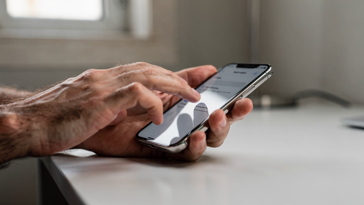 Mãos de uma pessoa interagindo com a tela de um iPhone 18, mostrando as configurações de rede onde se escolhe o plano de dados preferencial.