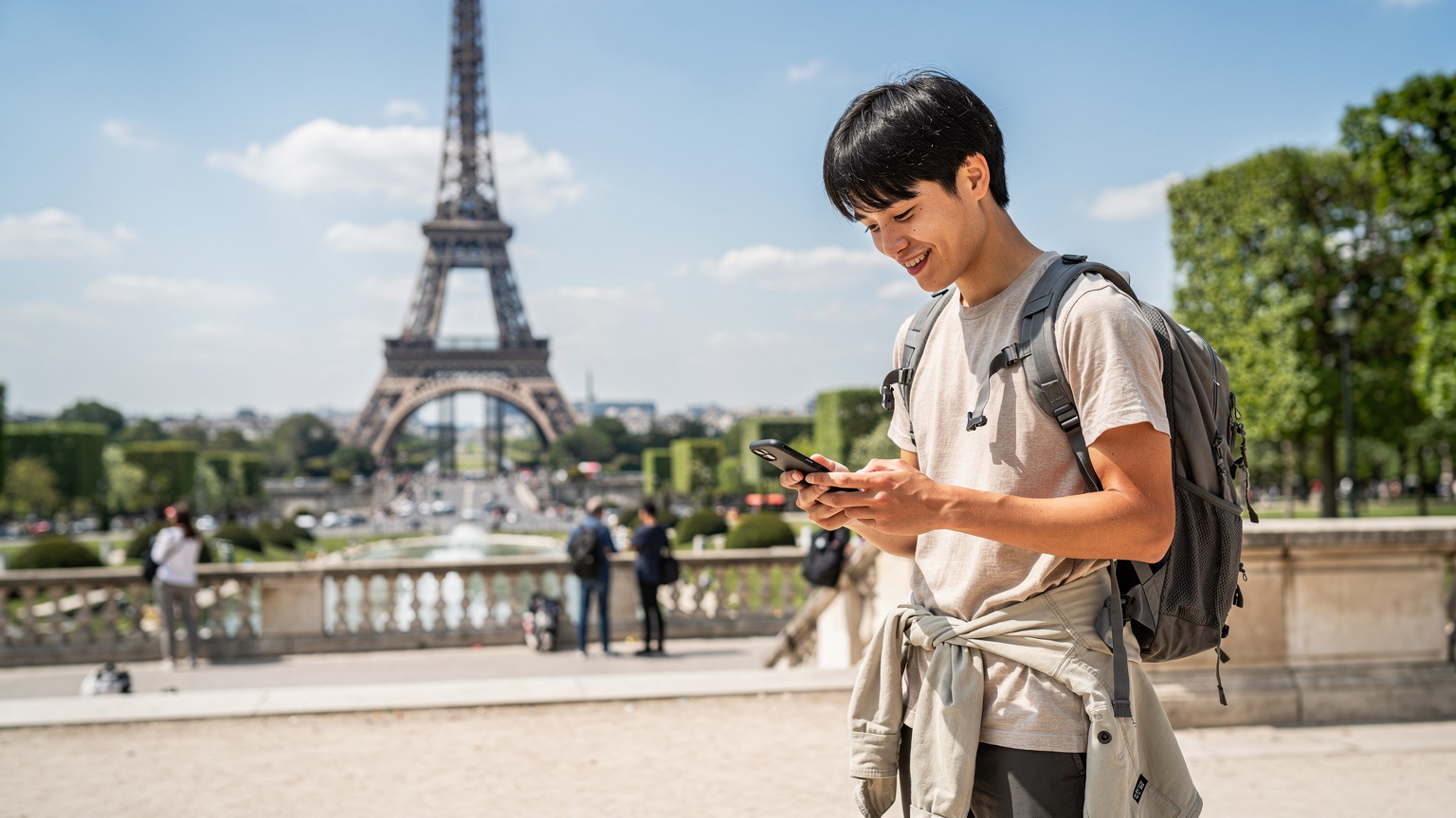パリのエッフェル塔を背景に、スマートフォンで地図アプリを確認しながら次の目的地を計画するバックパッカー。