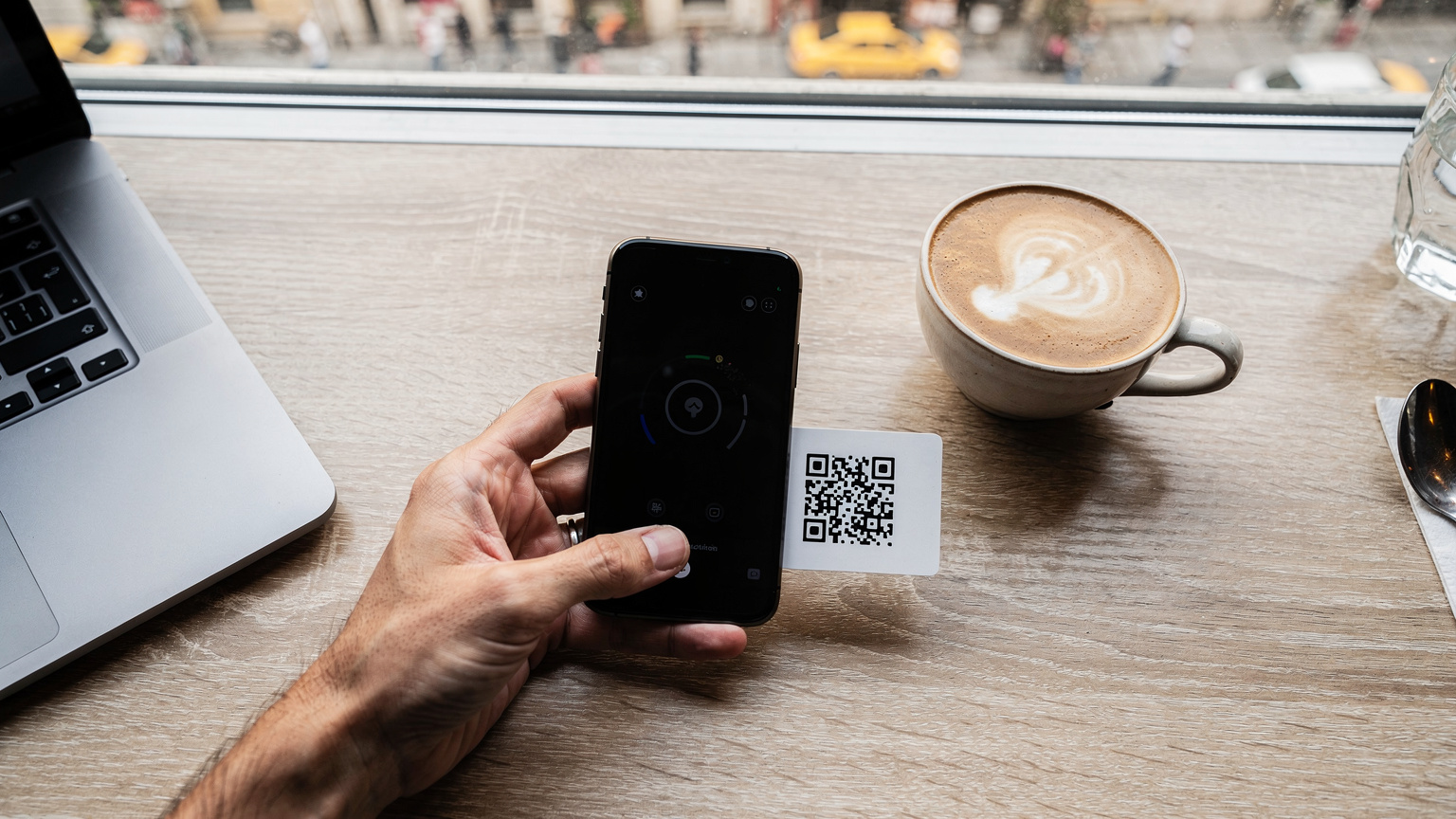Mână de călător ținând un telefon cu o interfață simplă de instalare eSIM, scanând un cod QR tipărit, într-o cafenea modernă din Beyoğlu, Istanbul.