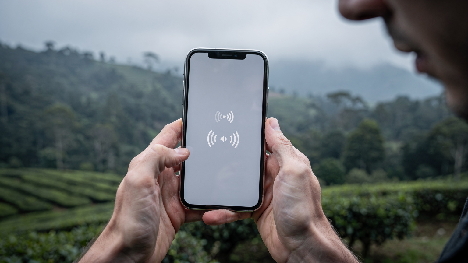 Tangan seorang pengembara memegang telefon pintar, memaparkan bar isyarat yang lemah di kawasan terpencil di pergunungan Cameron Highlands, Malaysia.