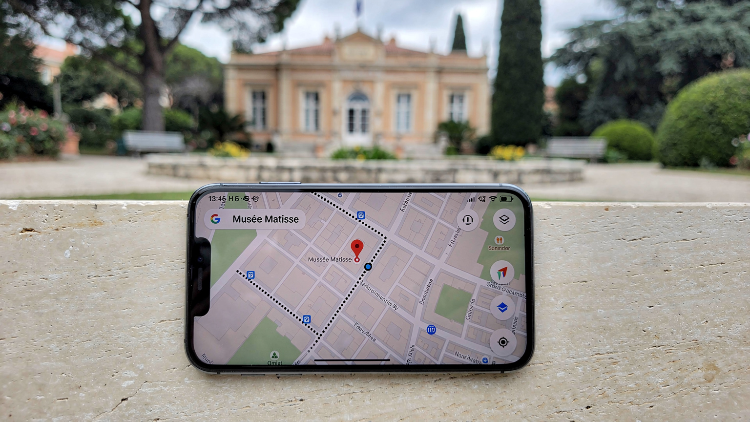 Ένα smartphone εμφανίζει την εφαρμογή Google Maps με μια διαδρομή πεζοπορίας προς το Musée Matisse στην περιοχή Cimiez της Νίκαιας, με το κτίριο του μουσείου να διακρίνεται αχνά στο βάθος.