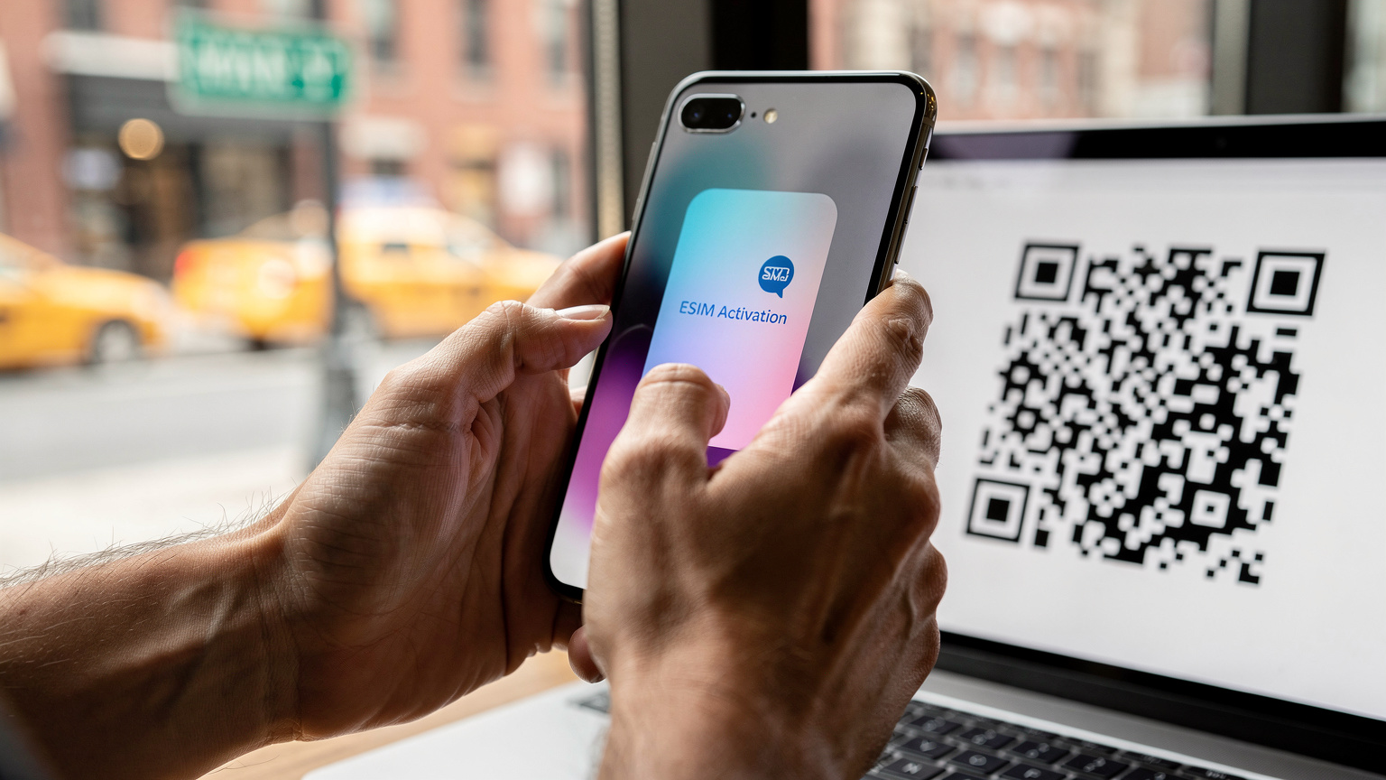 Un primo piano di mani che interagiscono con uno smartphone, mostrando il processo di scansione di un codice QR per attivare un'eSIM, con uno sfondo leggermente sfocato di una città americana.