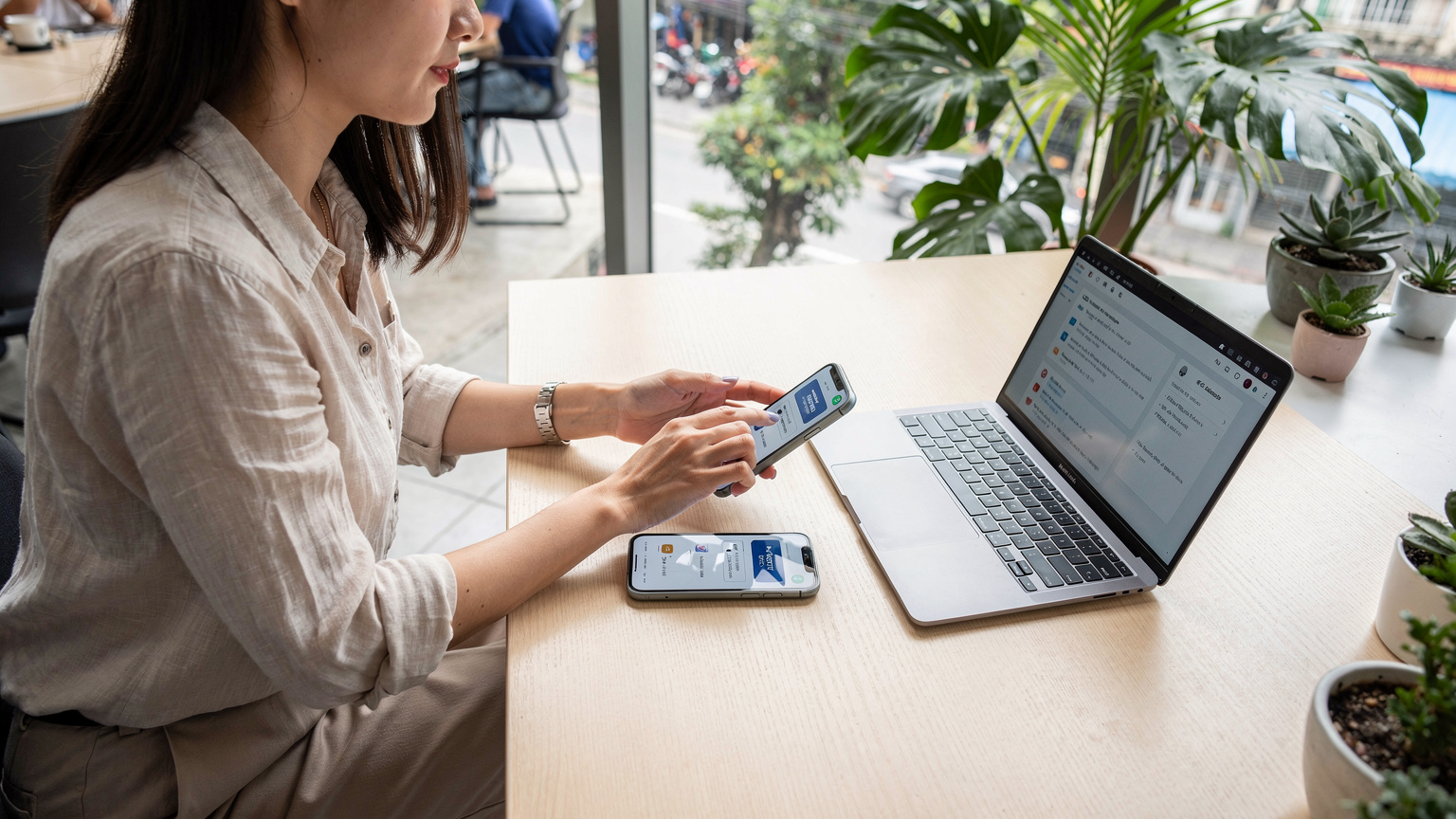 ベトナム、ホーチミンのコワーキングスペースで、ノートPCとiPhone 18を使ってeSIMのプラン選択を真剣に検討している日本人女性の様子。