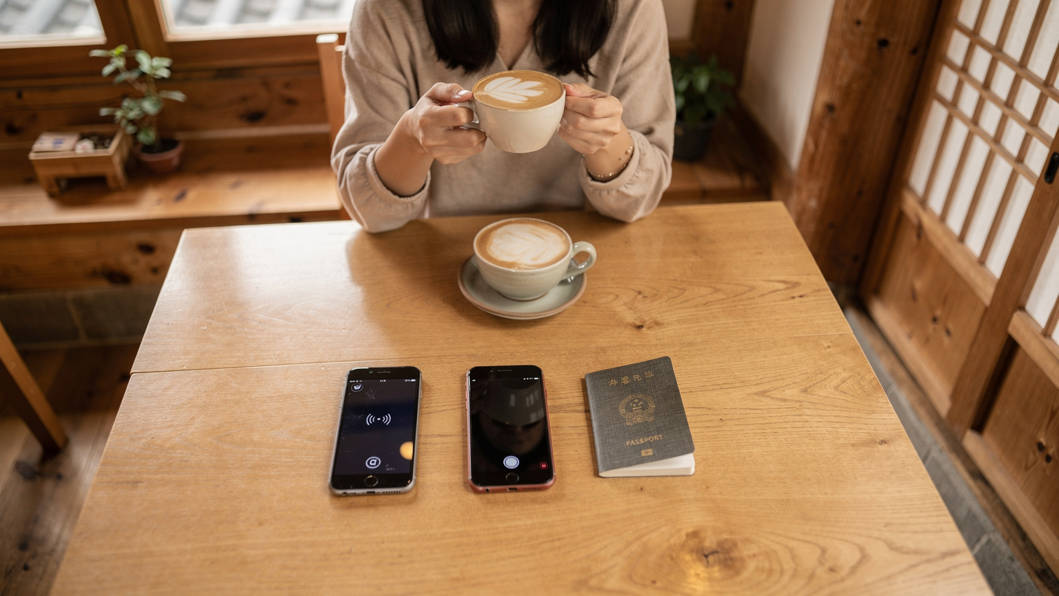 ソウルの伝統的な韓屋カフェで、旅行者がスマートフォンをテーブルに置き、コーヒーを飲みながらリラックスしている様子。スマホ画面にはWi-Fiアイコンが見える。