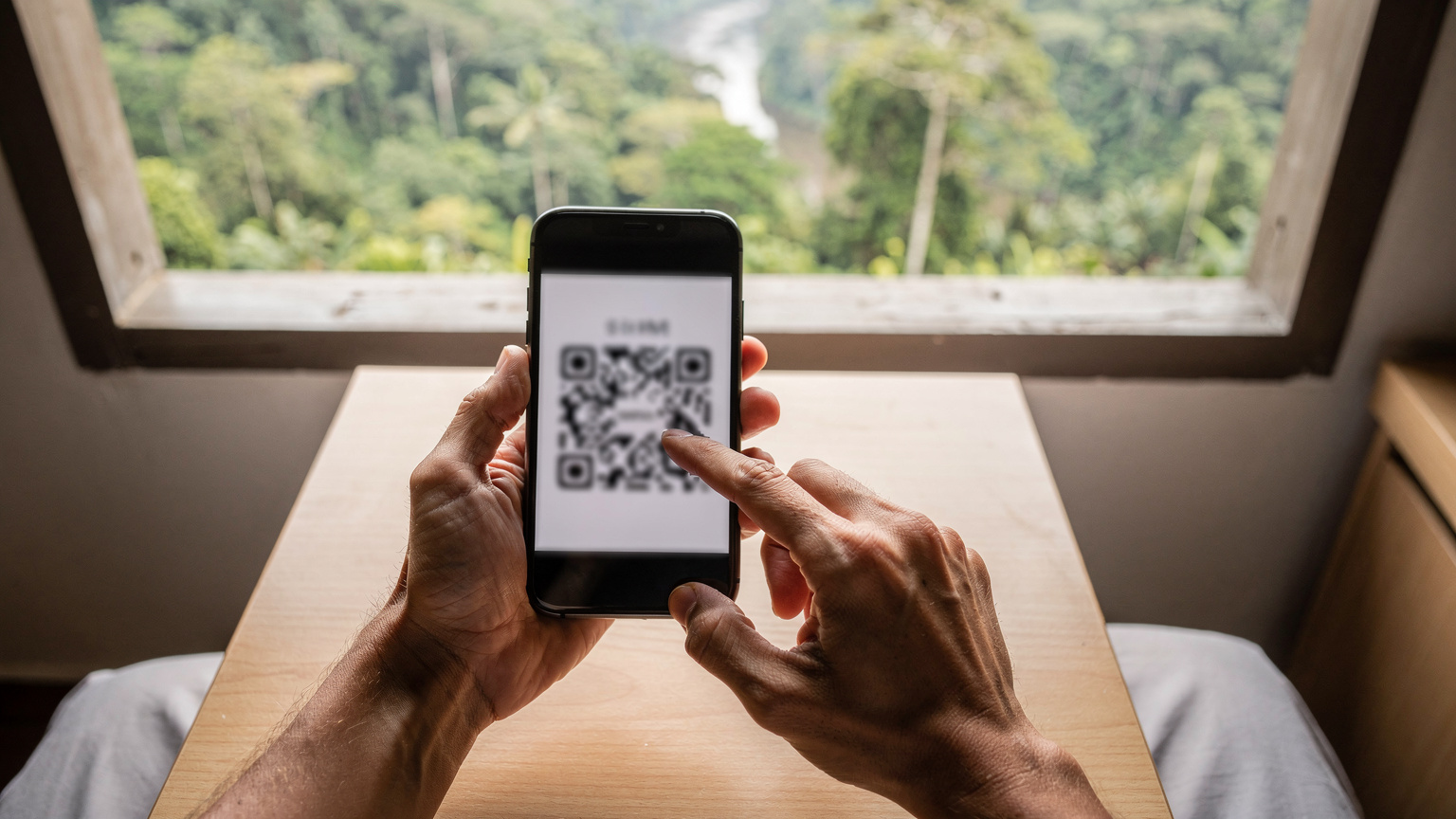 Tangan seorang pengembara Malaysia memegang telefon pintar dan mengimbas kod QR eSIM, dengan latar belakang pemandangan alam semula jadi Borneo yang indah di luar tingkap.