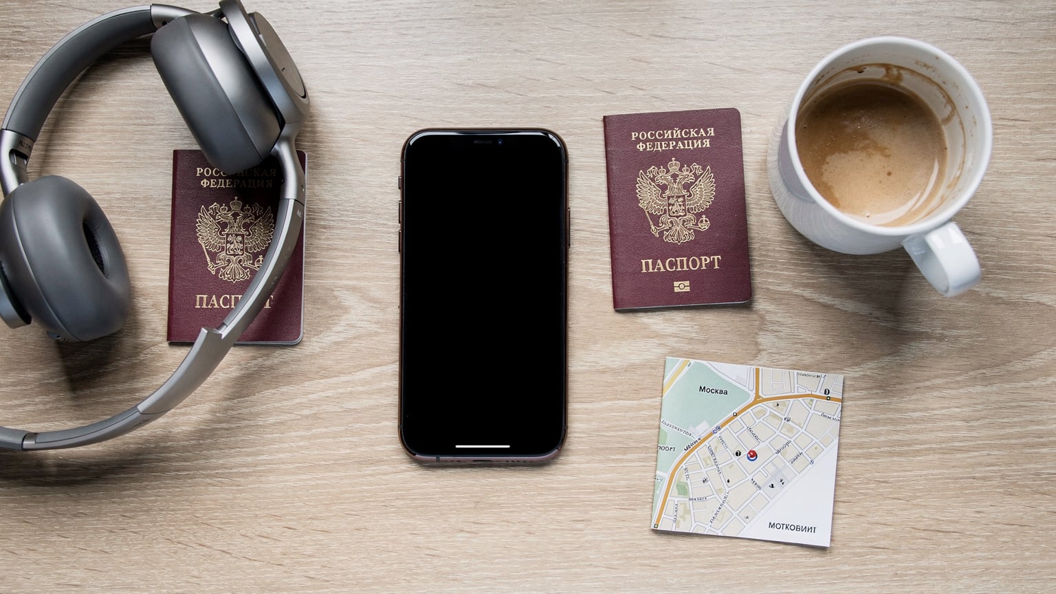 Элегантный плоский снимок рабочего стола цифрового кочевника с новым iPhone 18, паспортом, наушниками и чашкой кофе, символизирующий организованность и готовность к путешествиям.