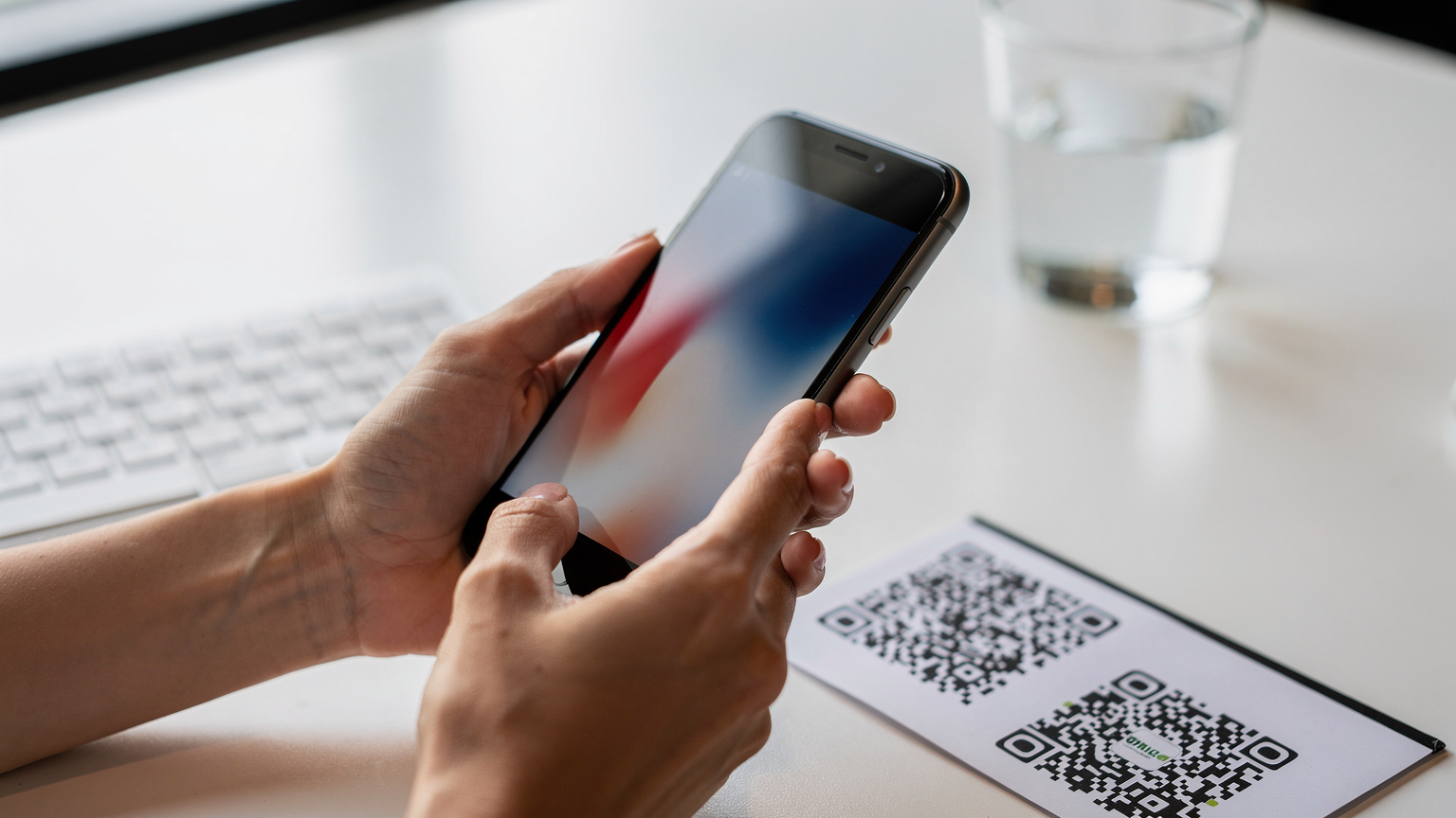 Gros plan sur les mains d'une femme utilisant son smartphone pour scanner un QR code, probablement pour activer une eSIM, dans un cadre lumineux et moderne.