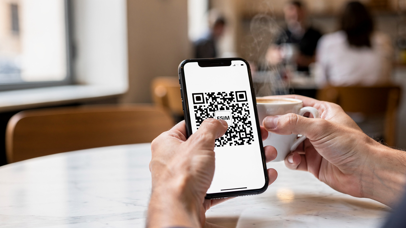 Primo piano di mani che tengono uno smartphone che visualizza un codice QR per l'installazione di un'eSIM, mentre l'altra mano regge una tazza di caffè fumante, in una caffetteria luminosa di Roma.