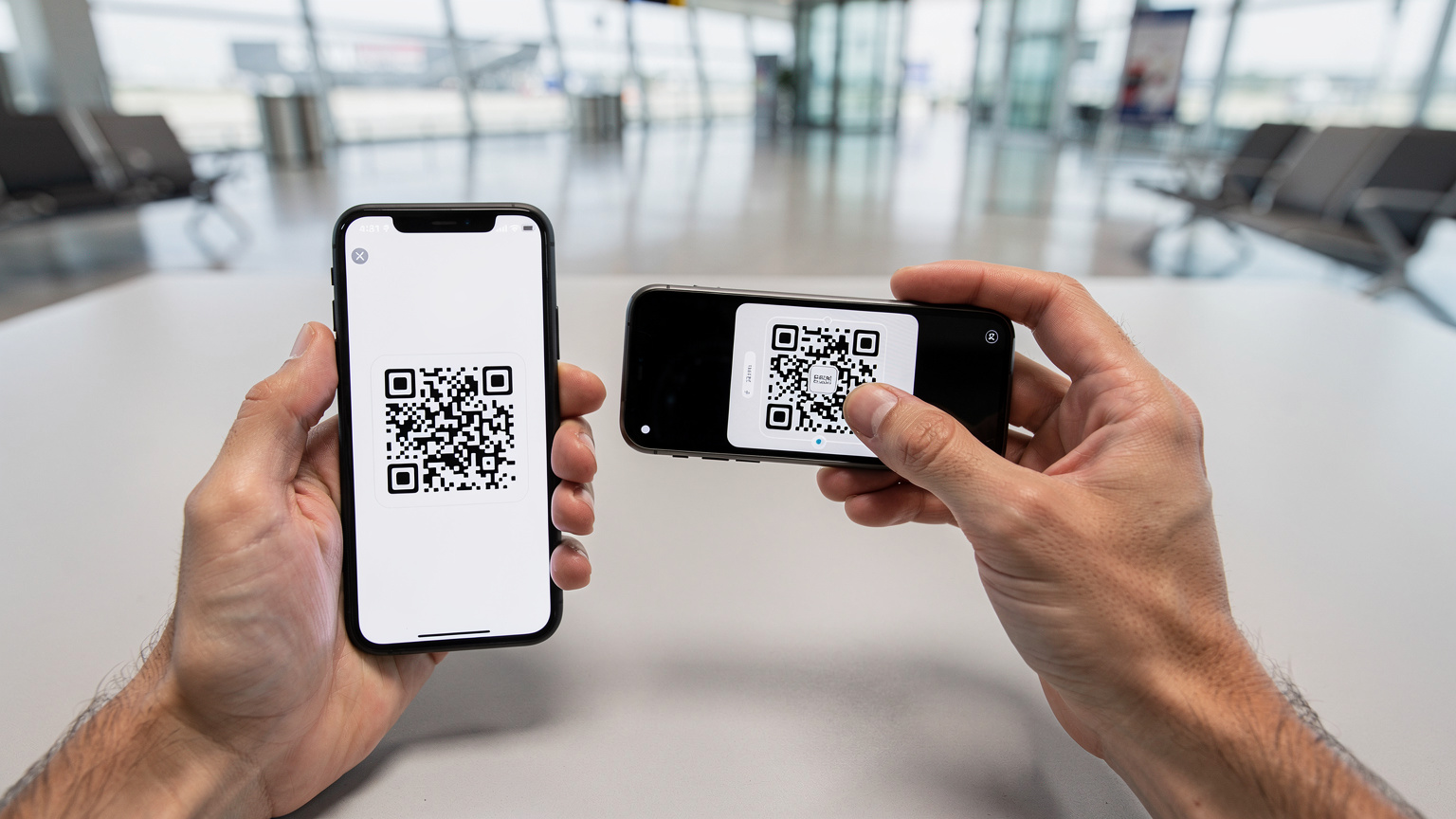 Havaalanı bekleme salonunda, bir akıllı telefonun ekranındaki QR kodu başka bir telefonla tarayan eller, eSIM kurulumunu gösteriyor.