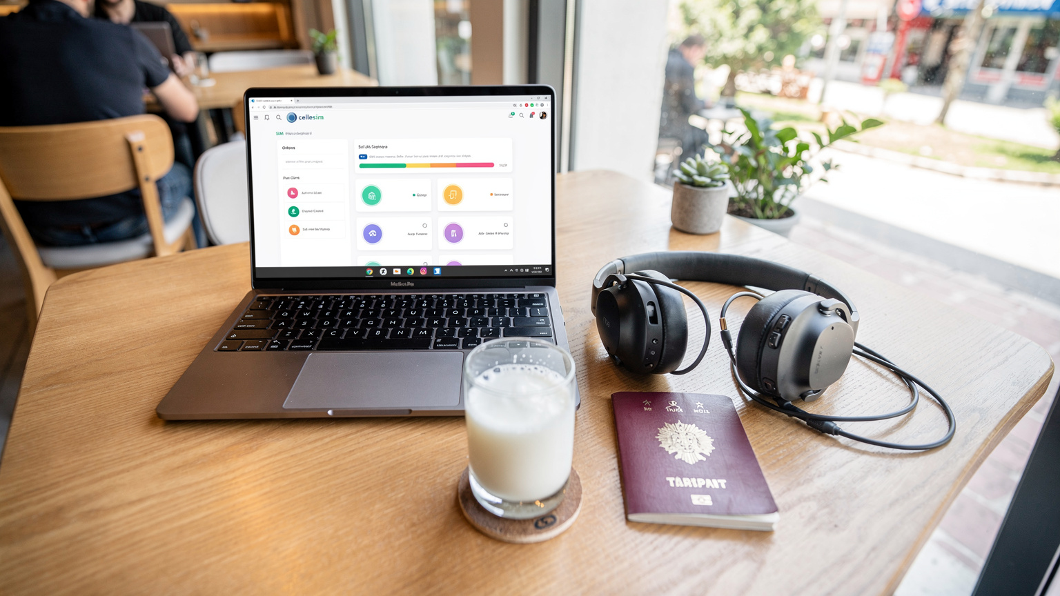 Bir dijital göçebe, pasaportu ve kulaklığıyla birlikte bir kafe masasında duran laptopunun ekranında Cellesim uygulamasını açmış, eSIM profilini yönetiyor.