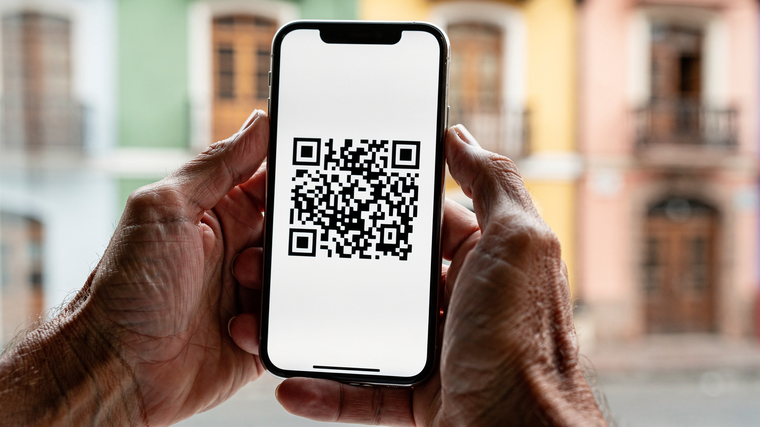 Nahaufnahme von Händen, die ein Smartphone halten, auf dem ein QR-Code für die eSIM-Aktivierung angezeigt wird, mit einer subtilen Andeutung einer ecuadorianischen Landschaft im Hintergrund.