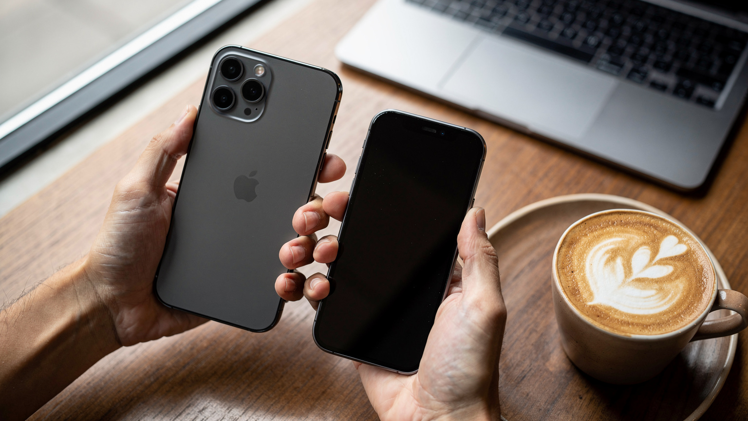 Dua tangan memegang iPhone berdekatan, sedang dalam proses transfer data atau eSIM, dengan latar belakang meja kayu di sebuah kafe modern di Jakarta Selatan, dengan secangkir kopi dan laptop di kejauhan.