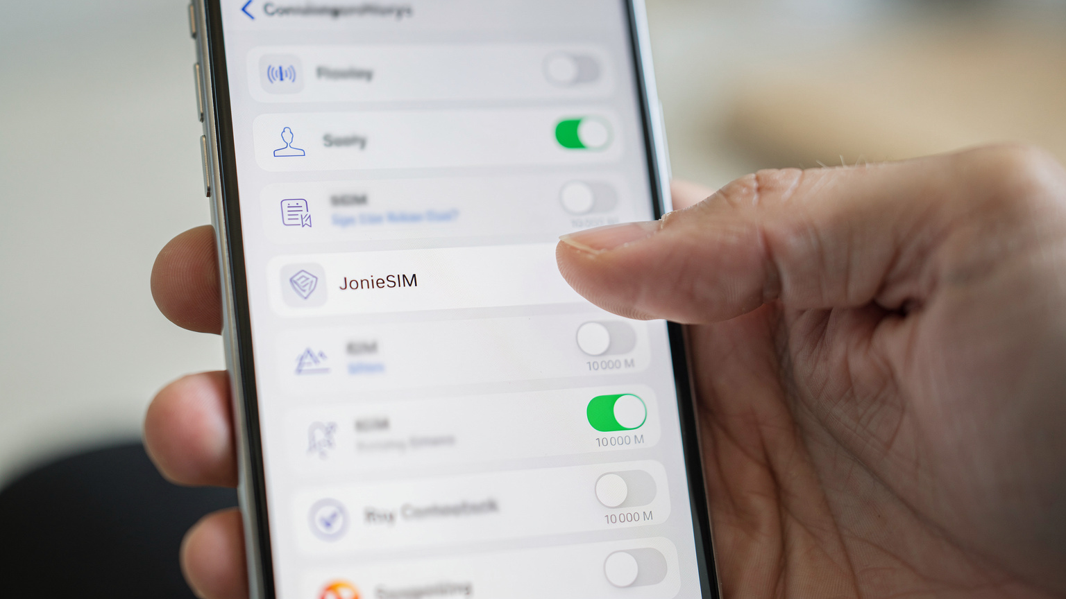 Un primer plano de la pantalla de un iPhone 15 mostrando los ajustes de "Datos móviles" o "eSIM", con un usuario seleccionando entre varias eSIM etiquetadas para diferentes regiones o propósitos.