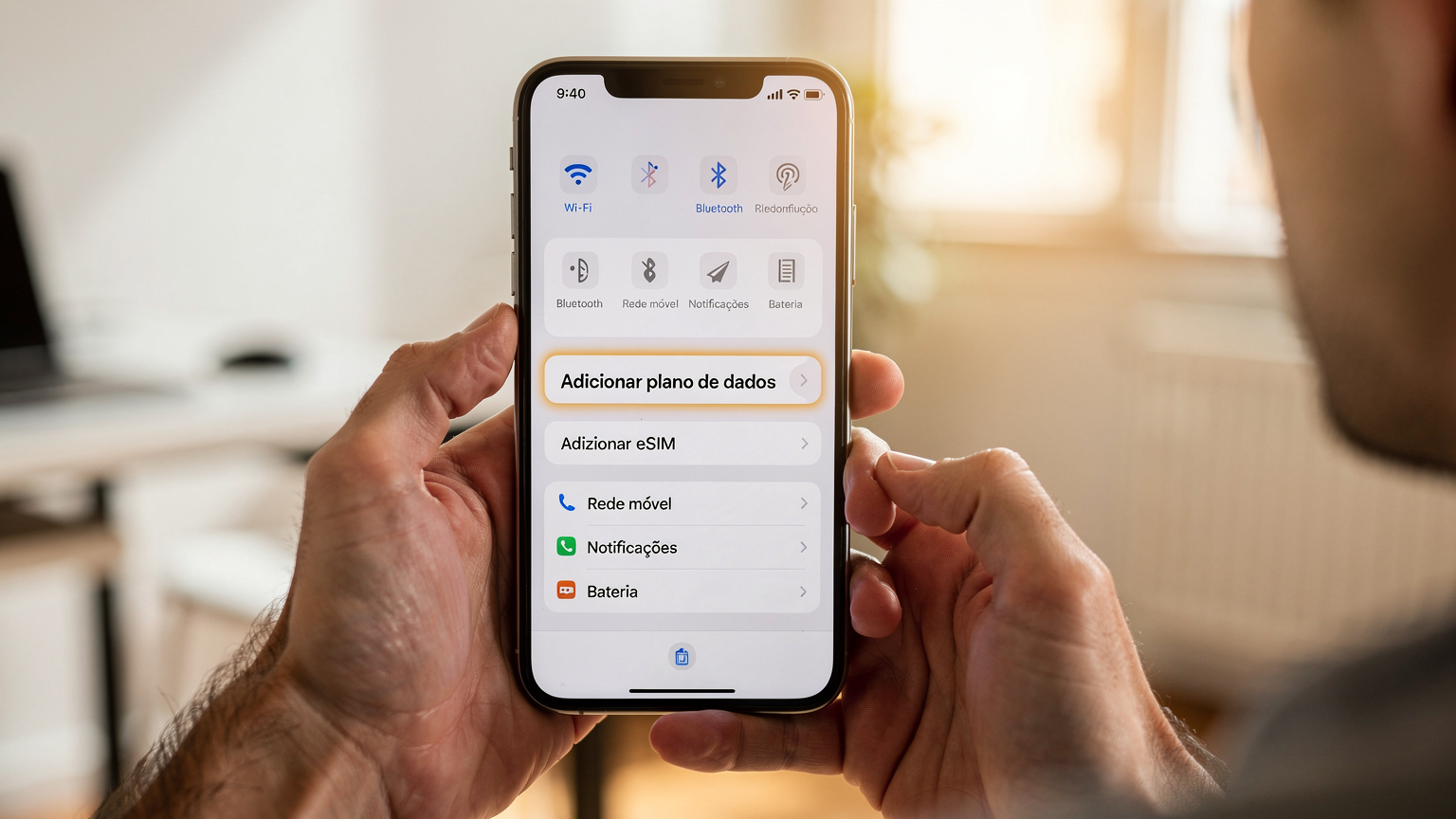 Mãos de uma pessoa segurando um smartphone com a tela exibindo as configurações de rede, com a opção 'Adicionar Plano de Dados' em destaque, num ambiente limpo e bem iluminado de um apartamento em Lisboa.