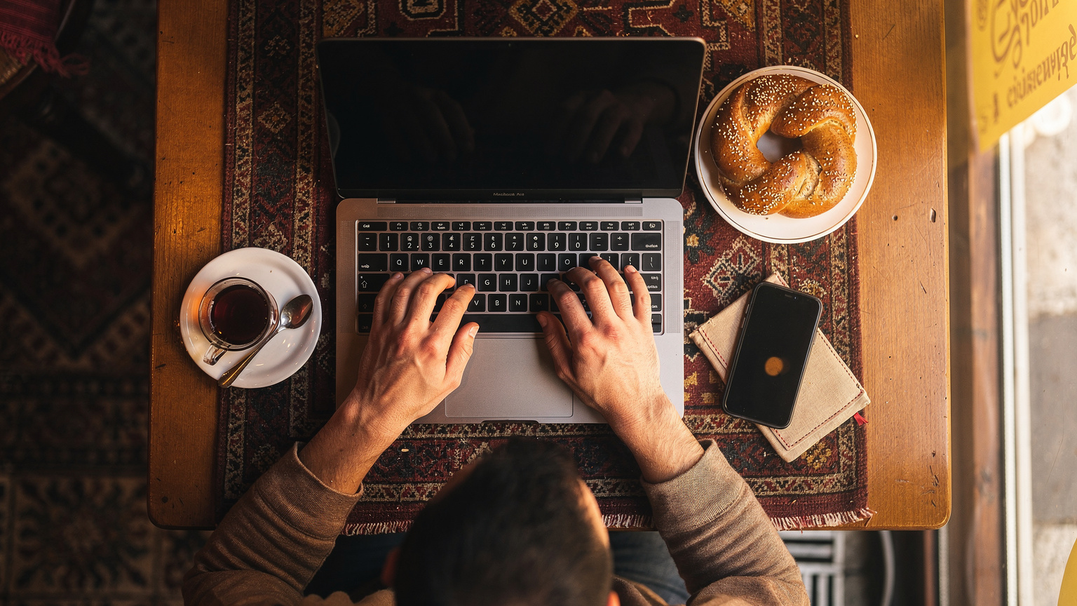 Vista aérea de un café en Estambul, con una persona trabajando en un portátil mientras disfruta de un té turco, simbolizando la vida nómada digital.