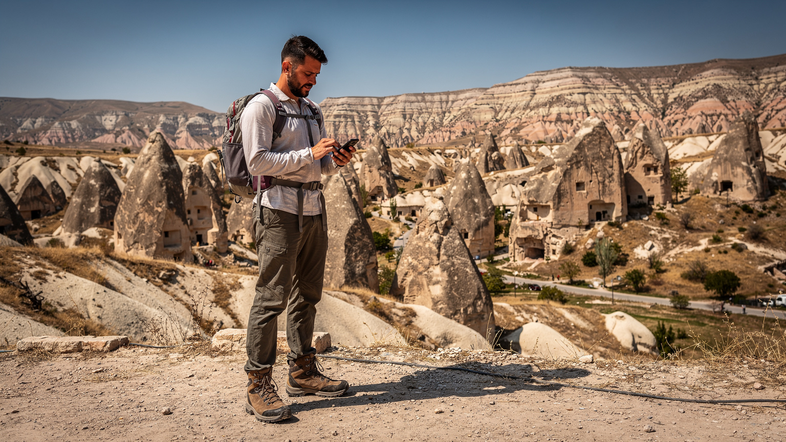 Un viajero en Capadocia usando su teléfono para orientarse, con las icónicas chimeneas de hadas al fondo.