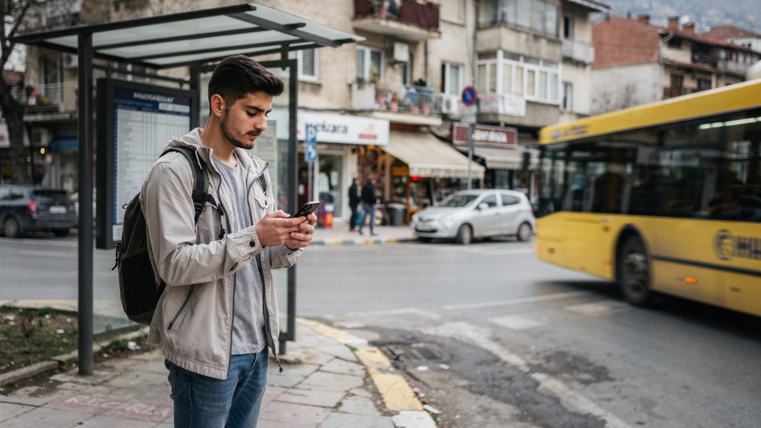 یک مسافر با تلفن هوشمند در دست، در حال بررسی وضعیت اتصال در ایستگاه اتوبوس در تیرانا، آلبانی.
