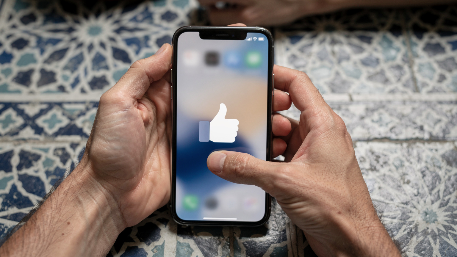 A close-up shot of hands holding a smartphone, with a thumbs-up gesture indicating successful eSIM activation, against a backdrop of Moroccan tile work.