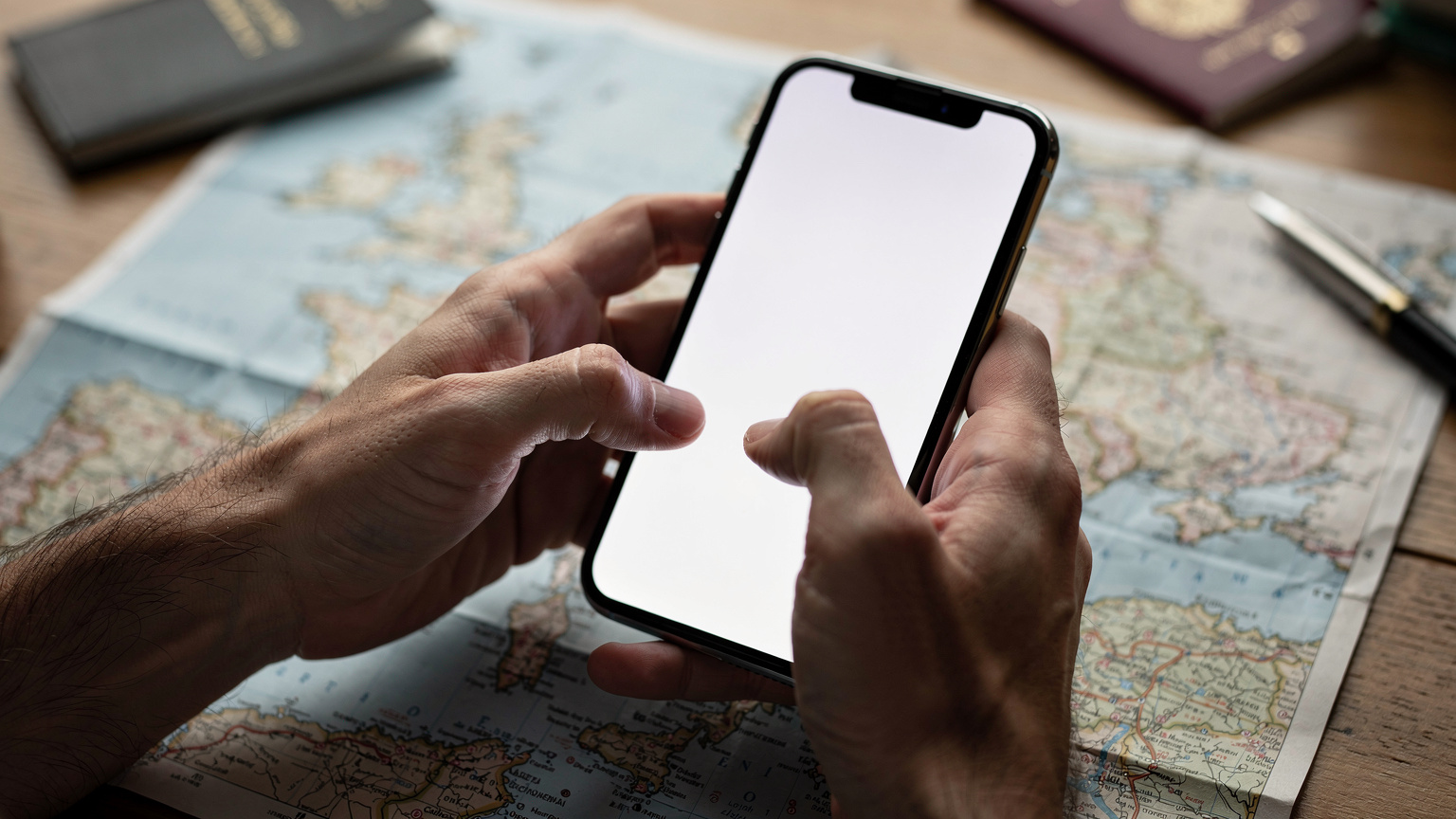 Ręce osoby trzymającej smartfon, na ekranie widać uproszczony interfejs aktywacji eSIM, w tle rozmazana mapa Europy na stole.