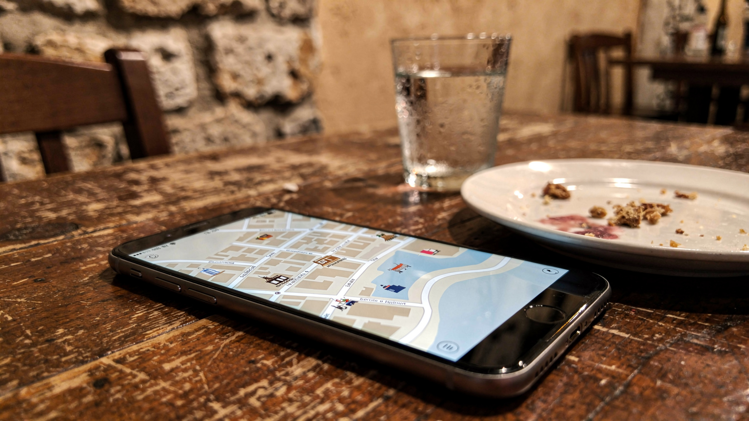 Eine Nahaufnahme eines Smartphones, das eine Offline-Karte von Split anzeigt, während es auf einem Holztisch in einem kroatischen Café liegt.
