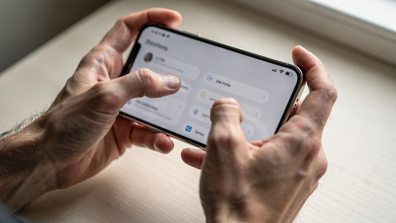 Nahaufnahme von menschlichen Händen, die ein Smartphone halten und durch die Einstellungen navigieren, um zwischen aktiven eSIM-Profilen zu wechseln. Der Bildschirm zeigt eine generische Menüoberfläche mit Optionen für 'Mobilfunk' oder 'SIM-Kartenverwaltung'.