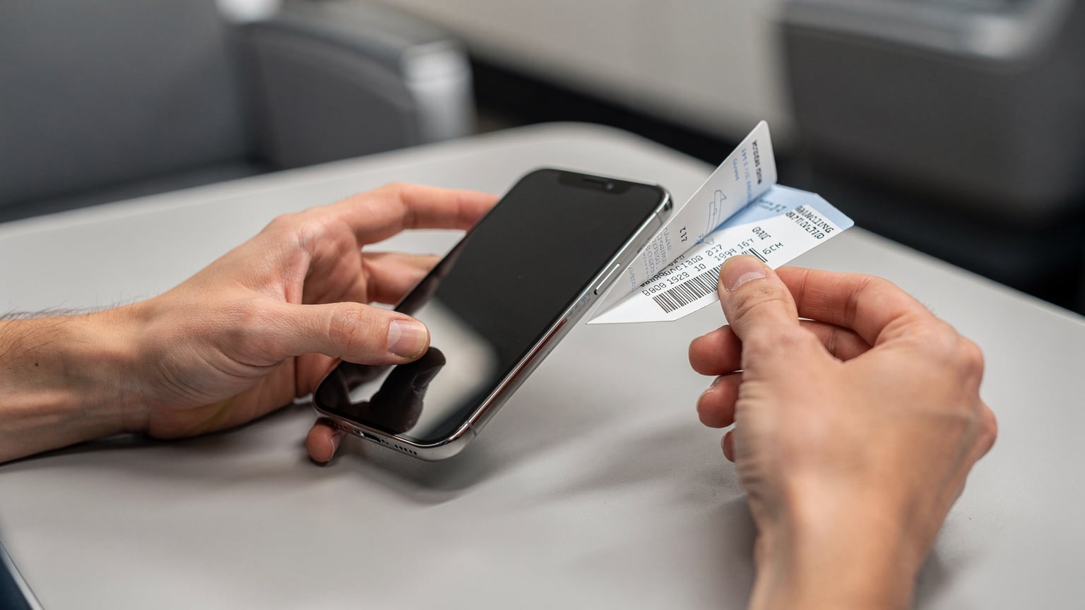 Mãos de uma pessoa segurando um smartphone com um aplicativo de eSIM aberto, enquanto a outra mão segura um cartão de embarque de avião, mostrando a preparação para uma viagem.