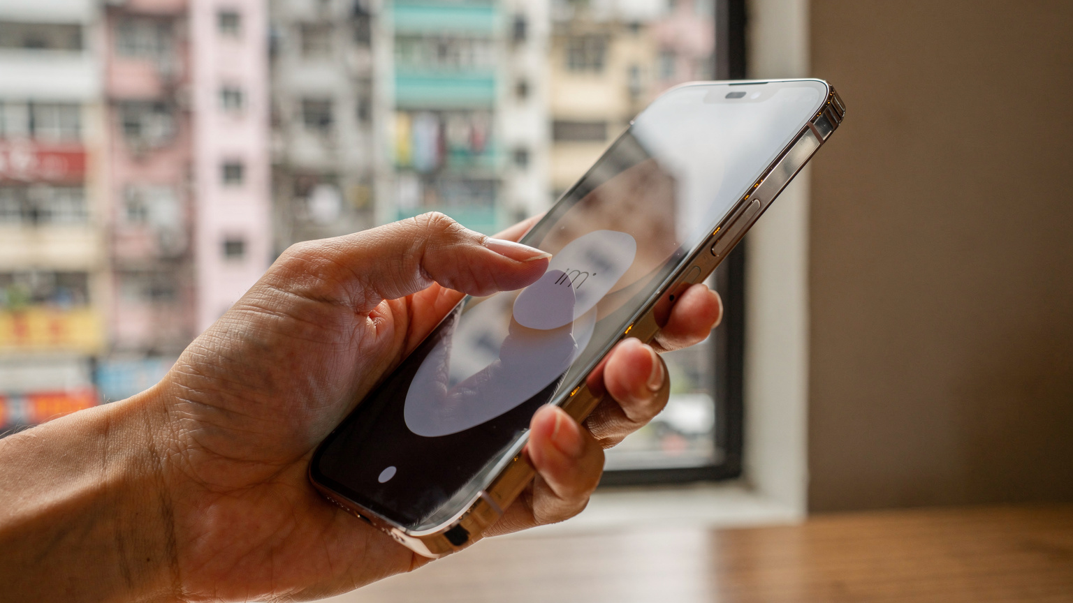 一隻手正在調整 iPhone 上的 eSIM 設置界面, 背景虛化, 隱約可見香港街頭的建築。